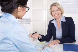 Zwei Frauen in Businesskleidung halten ein Gespräch in einem Büro